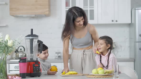 Cheerful Young Mother Laughing As Children Tasting Lemon