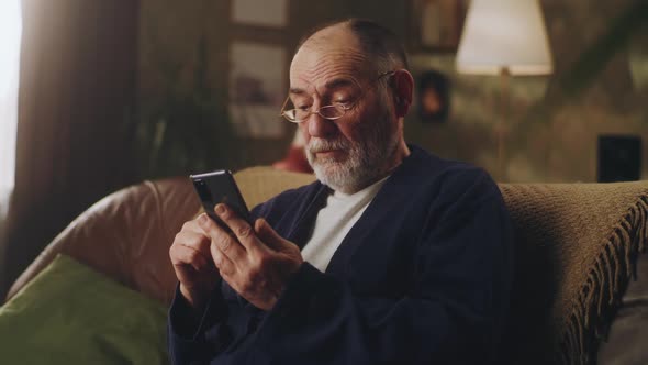 Senior Male Using Cellphone on Sofa