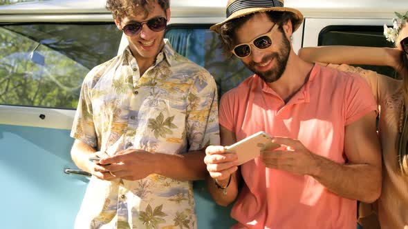 Hipster friends looking at smartphone and laughing