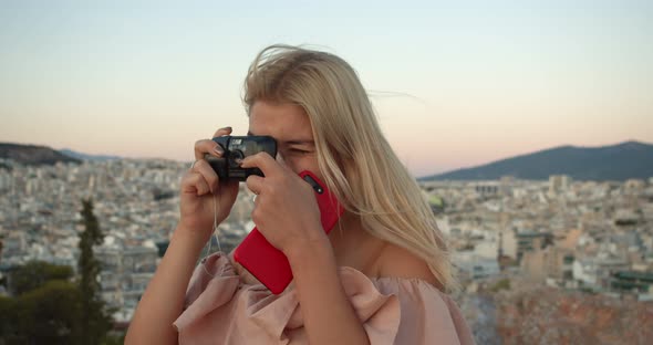a Woman at the Top of the Mountain Takes a Picture of the City on an Old Camera