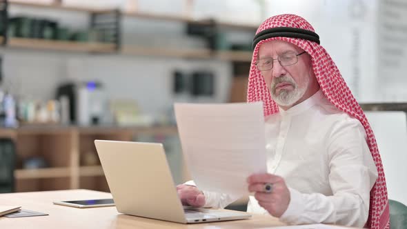 Senior Old Arab Businessman Working on Laptop and Documents 