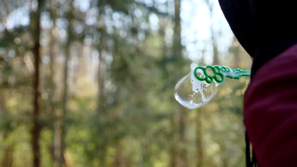 Girl in a Jacket in the Spring in the Forest Launches Soap Bubbles