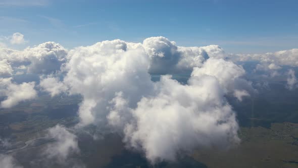 Aerial View From Airplane Window at High Altitude of Earth Covered with White Puffy Cumulus Clouds