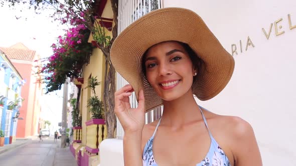 Stylish woman in summer outfit walking near colorful building