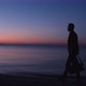 Silhouette of a man with a bag at dawn by the sea. - VideoHive Item for Sale