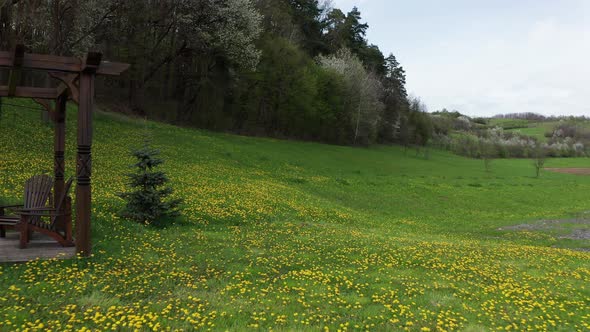 Wooden Chairs And Pergola In The Middle Of Beautiful Flower Field At Daytime. drone pullback