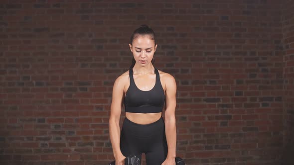 Fitness Young Woman in Black Sportswear Engaged with Dumbbells in the Gym