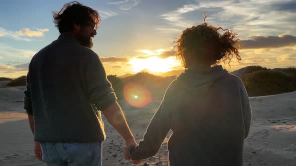 Romantic adult mature couple in love enjoying together an amazing outdoors sunset holding hands