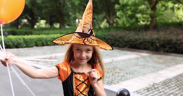 Cute Little Caucasian Girl with Blonde Hair Seven Years Old in Costume of Witch with Hat and Black
