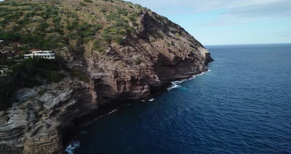 Drone shot of a cliffside beach that has both amazing houses and a nice views of the waves crashing