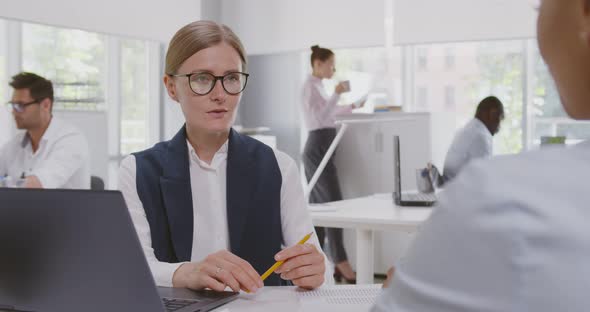 Confident Caucasian Female Manager in Glasses Consulting Client at Meeting in Office