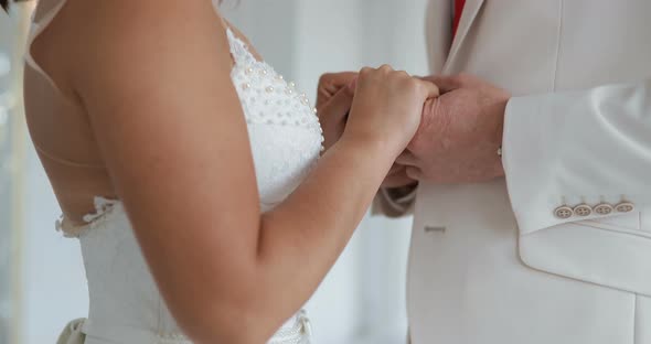 Bride and Groom Hold Hands and Look Each Other in the Eye