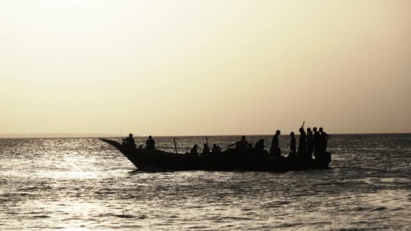 Silhouette of an African Fishing Boat with Fisherman Sailing in Ocean at Sunset