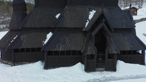 Borgund Stave church Norway - Winter low altitude aerial rotating slowly around entrance