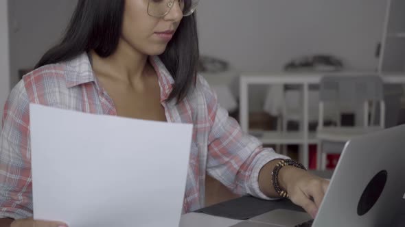 Concentrated Young Employee in Eyeglasses Working While Sitting at Table