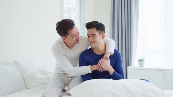 Portrait of Asian handsome man gay family hug and look at camera sitting on bed in bedroom.