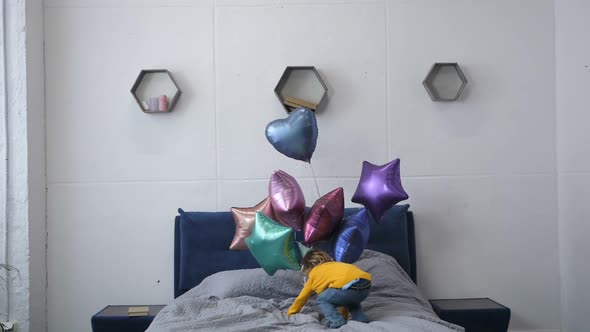  Little Boy Jumping on Bed with Baloons