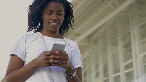 Smiling African American Woman Using Smartphone During Stroll