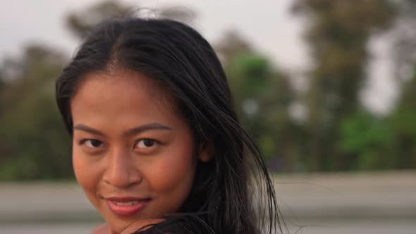 Beautiful Young Woman Looking At Camera On Beach At Sunset