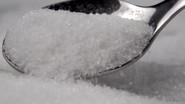 A teaspoon in a heap of white granulated sugar