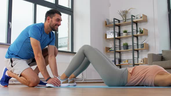 Woman with Personal Trainer Doing Sit Ups at Home