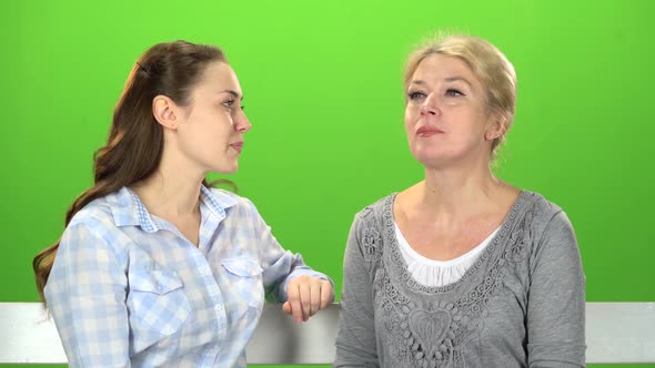 Mom and Daughter Are Sitting on a Bench. Green Screen