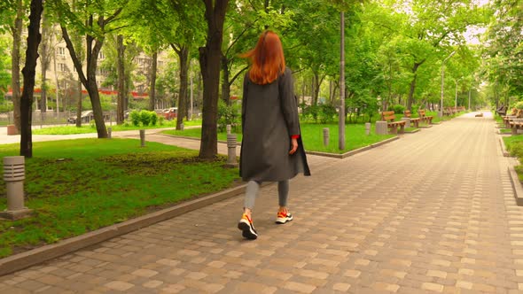 Redheaded Businesswoman Walks Outdoors
