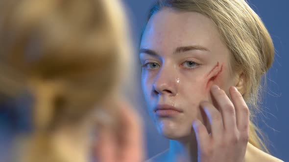 Crying Teen Girl Looking at Wound on Face in Mirror, Domestic Violence Victim
