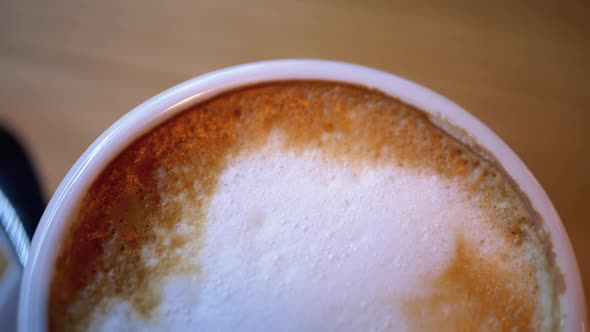 Cup of Cappuccino with White Foam on the Wooden Table in the Restaurant. Close-up