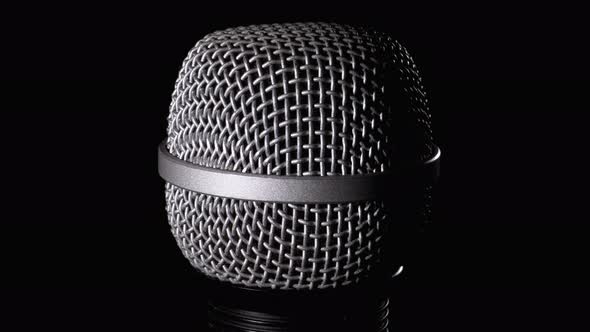 The Microphone Rotates on a Black Background. Dynamic Microphone Grid Spins Close-up