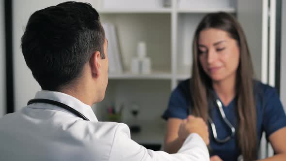 Smiling Female Professional Doctor Handshakes Male Doctor Agree to a Deal