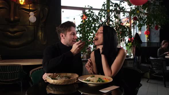 A Man Feeds a Girl with Chopsticks and Then Kisses Her Greedily