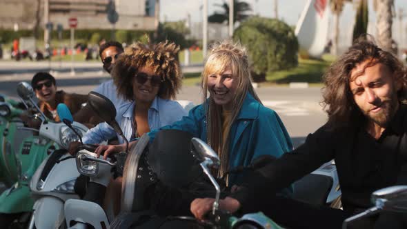 Trendy Young Friends on Scooters Waving at Camera