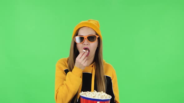 Portrait of Modern Girl in Yellow Hat in 3D Glasses Is Watching an Exciting Movie and Eating Popcorn