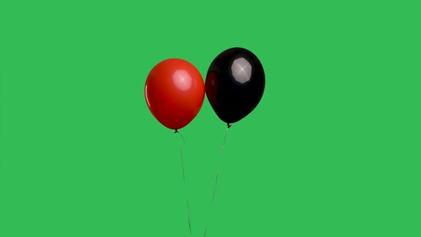 Red and Black Balloons Hanging in Air Against Background of Green Screen Chroma Key