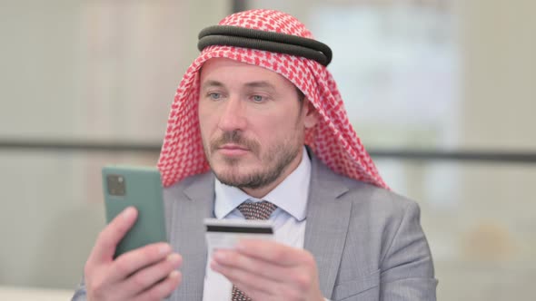 Portrait Middle Aged Arab Businessman with Successful Online Payment on Smartphone