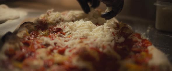 Chef spreading a mozzarella cheese over a traditional al taglio pizza. Slow motion.