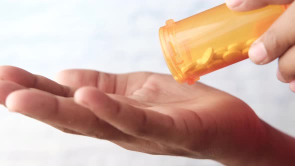 Man's Hand with Medicine Spilled Out of the Pill Container