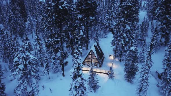 Little Hut in Mountain Covered with Snow. Flying with Drone Over the Forest and Beautiful Chalet.