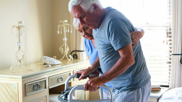 Senior woman helping man to walk with walker