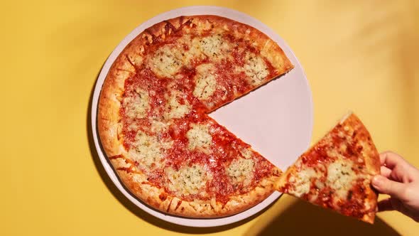 Kid hand taking slice of vegetarian home made pizza with vegan cheese and tomato sauce.