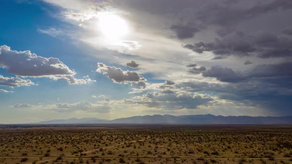 Heavy storm clouds obscuring sun over Mojave Desert landscape, Aerial Hyperlapse