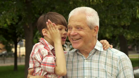 Little Boy Whispers in His Grandpa's Ear