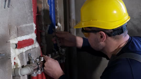 A Male Plumber Checks the Water Supply Pipes in the House Worker Hands Fixing Heating System