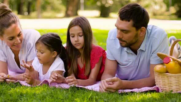 Family Lying on Picnic Blanket in Summer Park