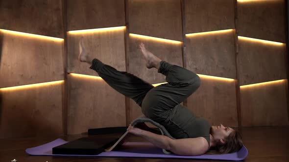 a Woman is Lying on a Sports Mat Against a Wooden Wall