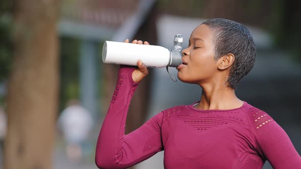 Profile Portrait of Young African American Sporty Woman Drinking in Park After Jogging