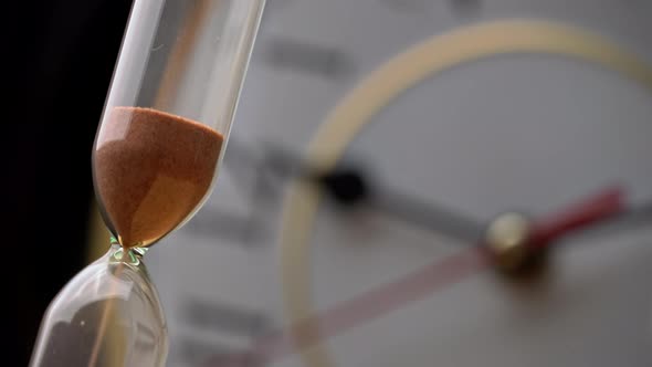 Hourglass Closeup is Pouring Against the Background Ordinary Mechanical Watch