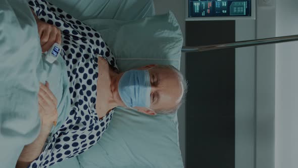 Vertical Video Portrait of Old Patient with Face Mask Sitting in Hospital Ward