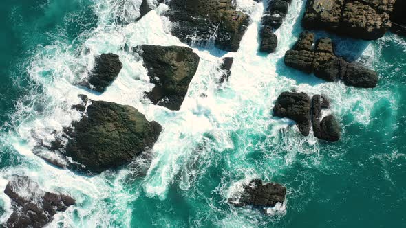 ocean blue waves break on high cliff of a rocky mountain.